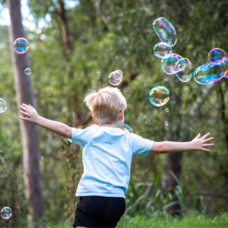 young boy chasing bubbles